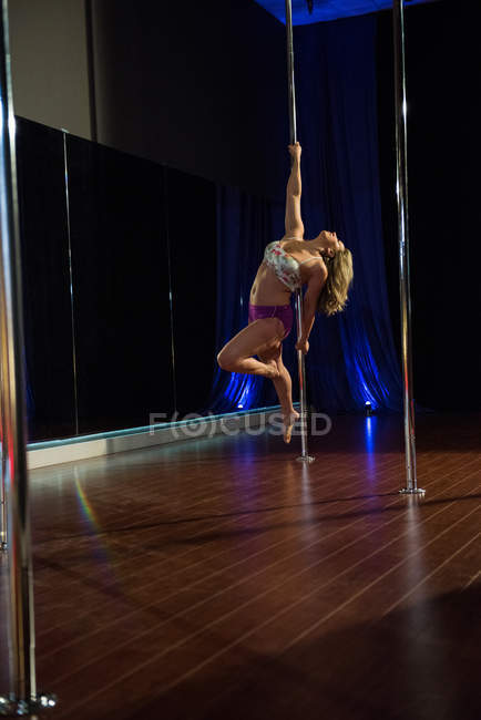 Sportliche Pole-Tänzerin übt Pole Dance im Studio — Stockfoto
