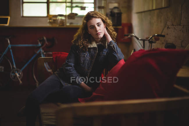Portrait of beautiful mechanic sitting on bench in workshop — Stock Photo