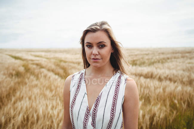 Retrato de la mujer de pie en el campo de trigo en el día soleado - foto de stock