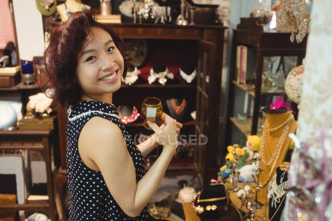 Портрет улыбающейся женщины, выбирающей чашку в антикварных ювелирных магазинах — стоковое фото
