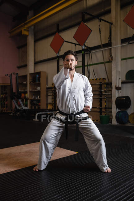 Vue de face de l'homme pratiquant le karaté dans un studio de fitness — Photo de stock