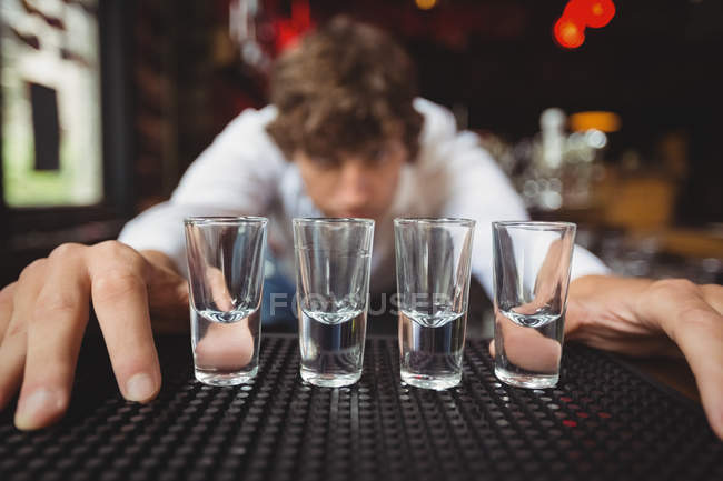 Bartender preparing and lining shot glasses for alcoholic drinks on bar counter at bar — Stock Photo