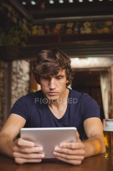 Man using digital tablet with beer glass on table in bar — Stock Photo