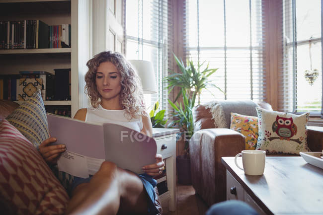 Schöne Frau liest Magazin im Wohnzimmer zu Hause — Stockfoto