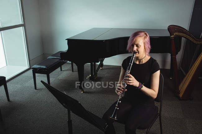 Hermosa mujer tocando un clarinete en la escuela de música - foto de stock