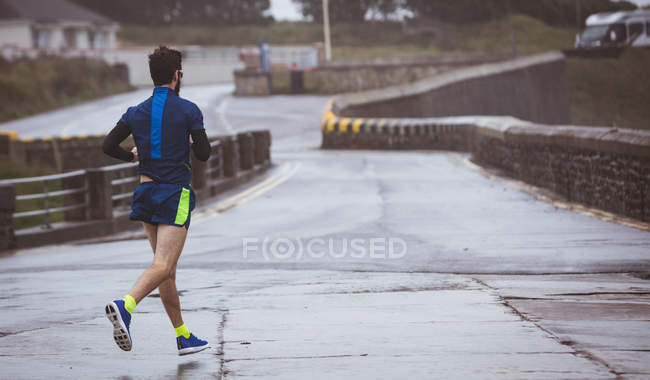 Atleta corriendo en la carretera durante el día - foto de stock