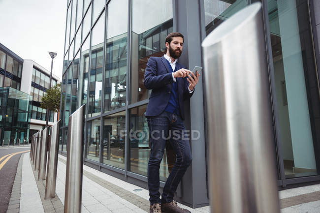 Homme d'affaires utilisant un téléphone portable à l'extérieur du bureau — Photo de stock