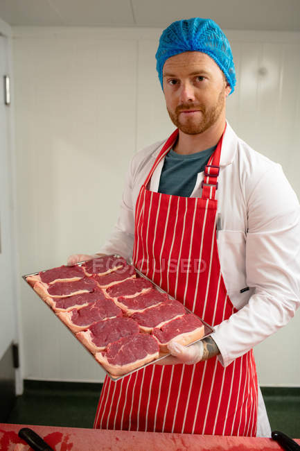 Мясник держит поднос стейков в мясной лавке — стоковое фото