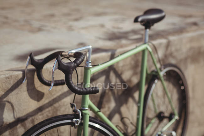 Bicicleta apoyada contra la pared en un día soleado - foto de stock