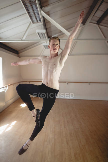 Jovem bonito bailarino pulando enquanto dança no estúdio — Fotografia de Stock