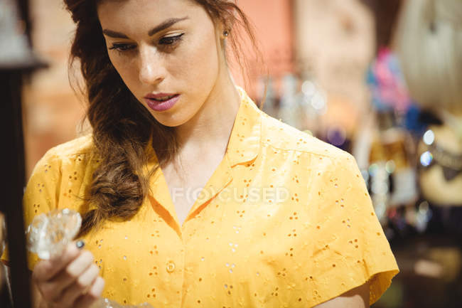 Mulher olhando para suporte de vela de vidro na loja de antiguidades — Fotografia de Stock