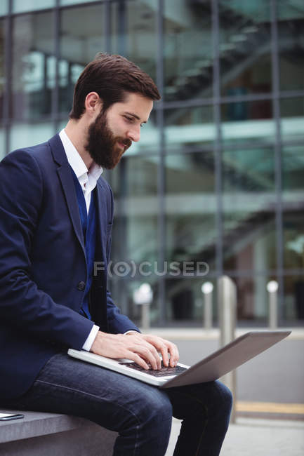 Hombre de negocios atento utilizando el ordenador portátil fuera de la oficina - foto de stock
