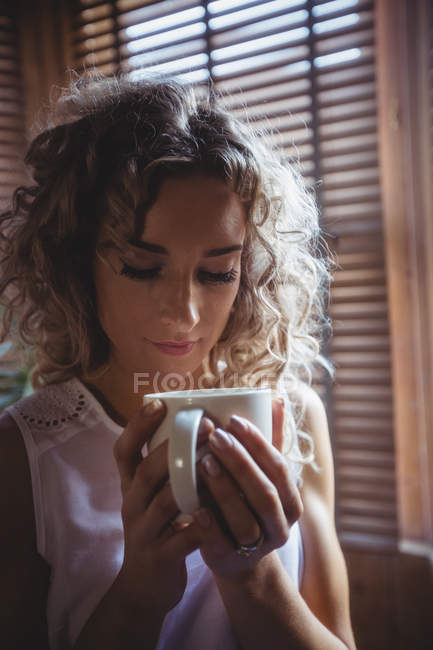 Close-up de mulher bonita tomando café na sala de estar em casa — Fotografia de Stock