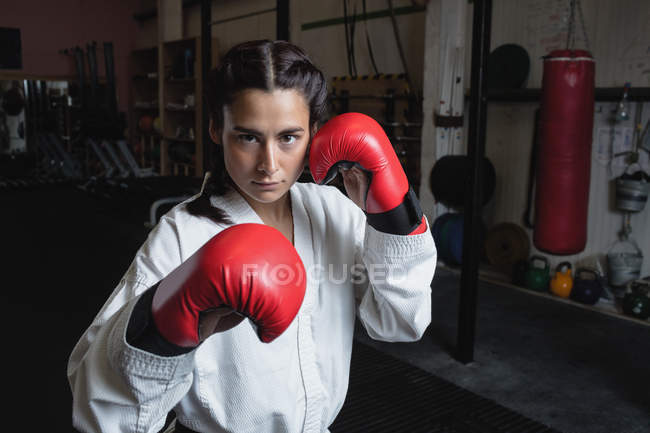 Porträt einer Boxerin in roten Boxhandschuhen, die im Fitnessstudio in die Kamera blickt — Stockfoto
