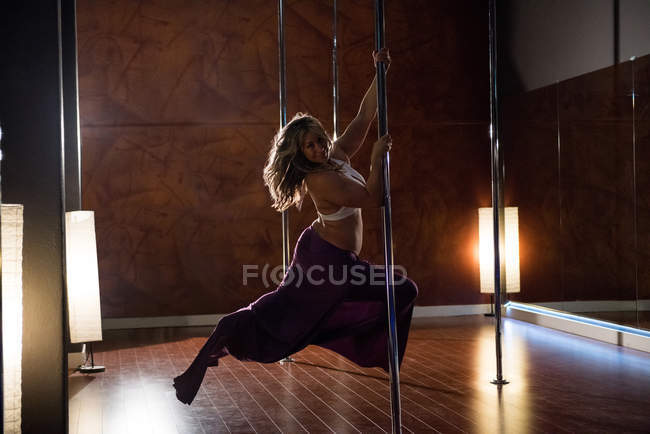 Leidenschaftliche Pole-Tänzerin übt Pole Dance im Studio — Stockfoto