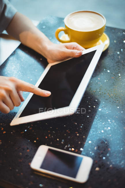 Крупним планом жінка використовує цифровий планшет, маючи каву в кафе — стокове фото
