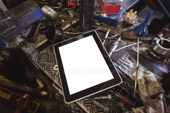 Tablet digital y herramientas en el banco de trabajo en el taller - foto de stock