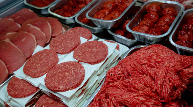 Close-up of raw hamburger patties and minced meat on display — Stock Photo