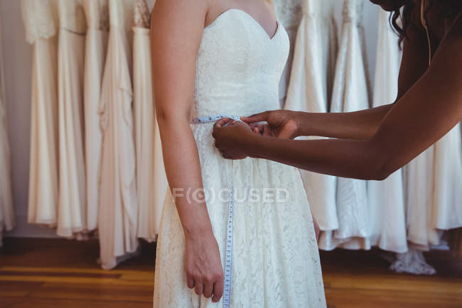 Жінка намагається на весільній сукні за допомогою дизайнера моди в студії — стокове фото