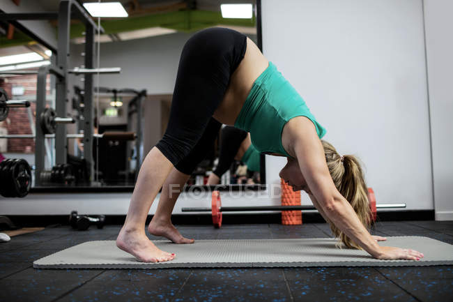 Беременная женщина, выполняющая упражнения на коврике в спортзале — стоковое фото