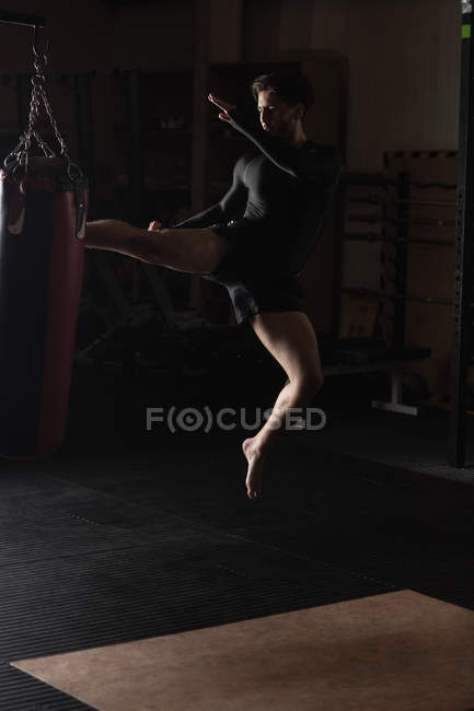 Boxer practicing boxing with punching bag in fitness studio — Stock Photo