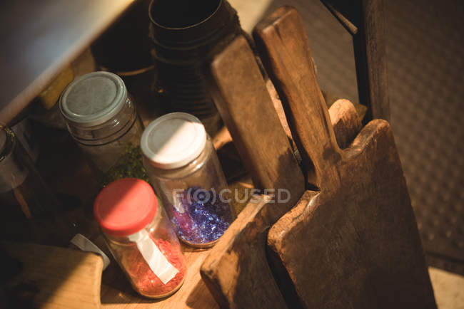 Стеклянные красящие ингредиенты и весло на полке на стеклодувном заводе — стоковое фото