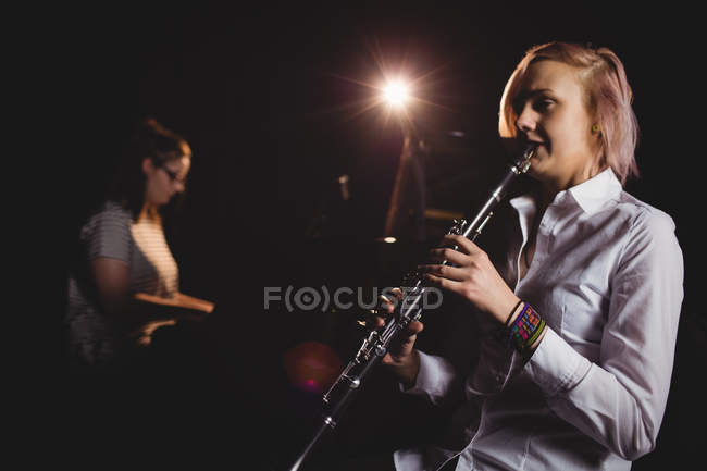 Dos alumnas tocando clarinete y piano en un estudio - foto de stock