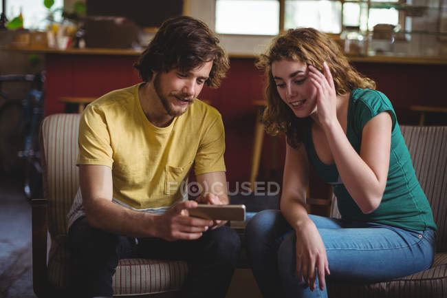 Mechanics sitting on sofa and using mobile phone in workshop — Stock Photo