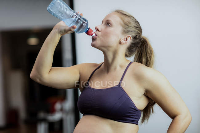 Femme enceinte boire de l'eau pendant la pause dans la salle de gym — Photo de stock
