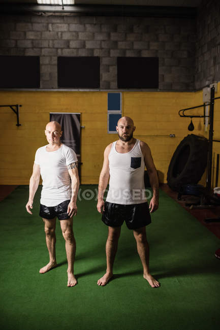 Retrato de dos boxeadores de pie en el gimnasio y mirando a la cámara - foto de stock