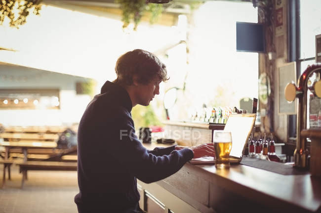 Mid section of man using laptop at bar counter — Stock Photo