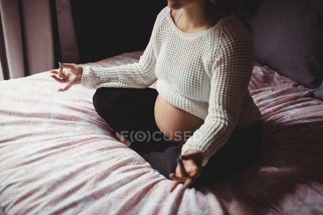 Geschnittenes Bild einer schwangeren Frau, die zu Hause im Schlafzimmer Yoga macht — Stockfoto