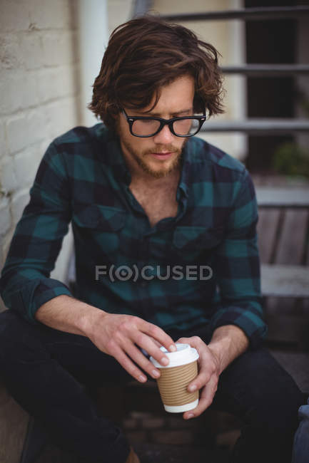 Mann sitzt auf Treppe und trinkt Kaffee vor Haus — Stockfoto