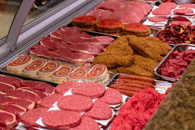 Variety of marinated meat at display counter in butchers shop — Stock Photo
