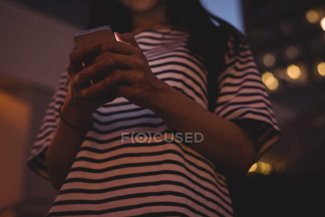 Mulher jovem usando telefone celular na cidade à noite — Fotografia de Stock