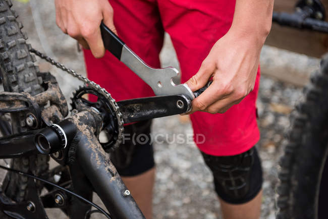A meio da seção do ciclista masculino reparando sua bicicleta na floresta — Fotografia de Stock