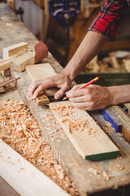 Hombre trabajando sobre una tabla de madera en el astillero - foto de stock