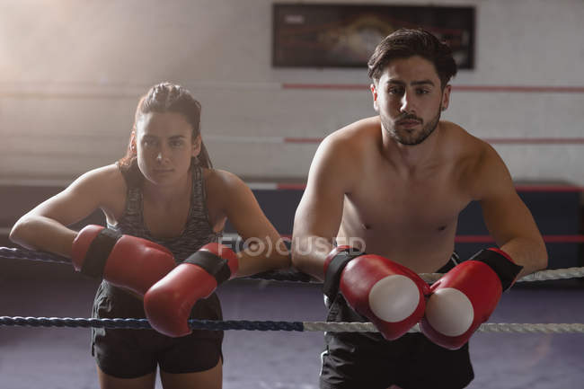 Retrato de boxers masculinos e femininos apoiados em cordas de boxe no estúdio de fitness — Fotografia de Stock