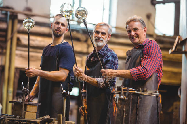 Retrato da equipe de sopradores de vidro que moldam um vidro nos blowpipes na fábrica de sopro de vidro — Fotografia de Stock