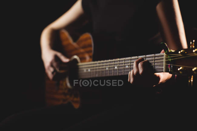 Étudiante de milieu de section jouant de la guitare dans un studio — Photo de stock