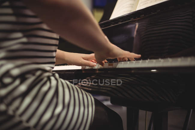 Sección media de alumna tocando el piano en un estudio - foto de stock
