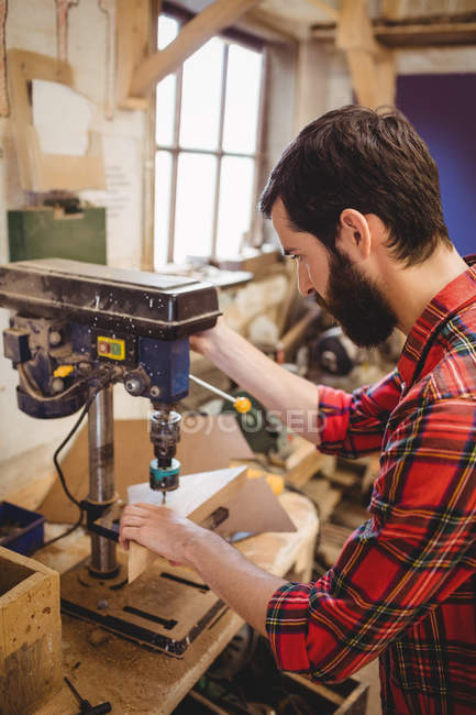 Man drilling a hole on wooden plank in boatyard — Stock Photo
