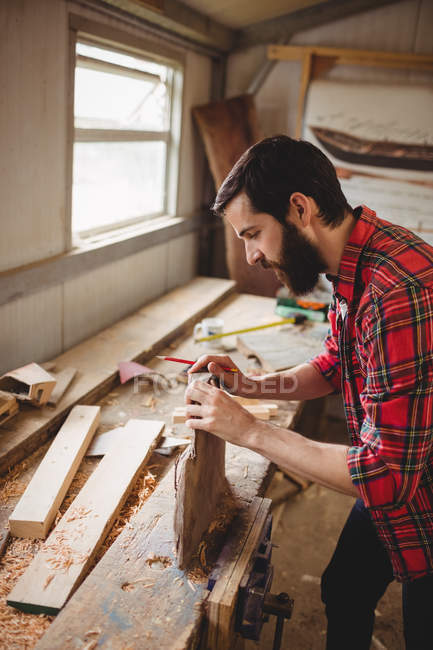 Man working over a wooden plank at boatyard — Stock Photo