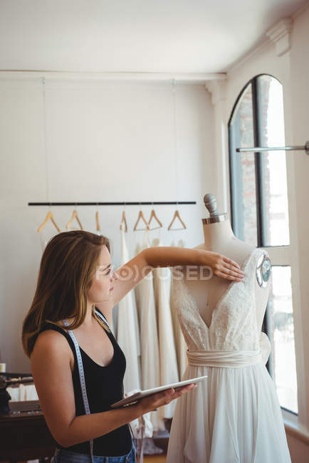 Жіночий дизайнер моди, що налаштовує сукню на манекен в студії — стокове фото