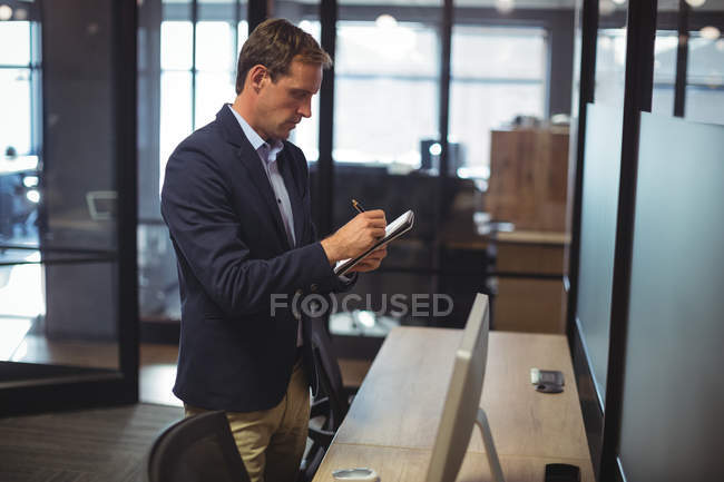 Businessman writing in diary at desk in office — Stock Photo