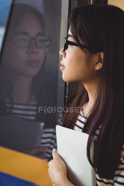 Mujer joven reflexiva mirando por la ventana - foto de stock