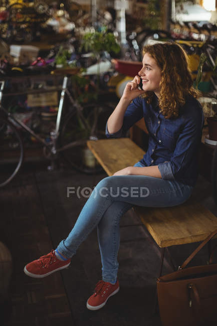 Красивая женщина разговаривает по мобильному телефону в мастерской — стоковое фото
