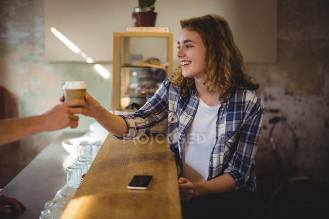 Mechanic receiving coffee from waiter at counter in workshop — Stock Photo