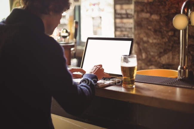 Людина використовує ноутбук на барній стійці — стокове фото