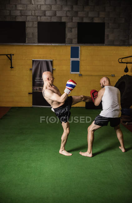Vista lateral de dos boxeadores tailandeses entrenando en gimnasio - foto de stock